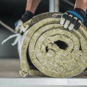 Construction Worker Preparing Roll of Mineral Wool Insulation